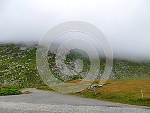 Clouds floating down over mountain top Gotthard at 2.106 m 6,909Â ft height in Switzerland